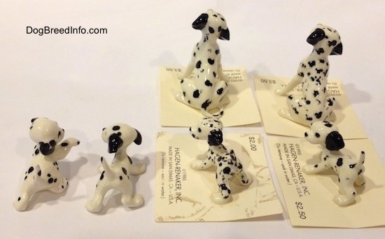 The back of six Dalmatian figurines, two are full grown Dalmatians and four are puppies. The puppies have long tails that are arching up and the full grown figurines have thin tails.